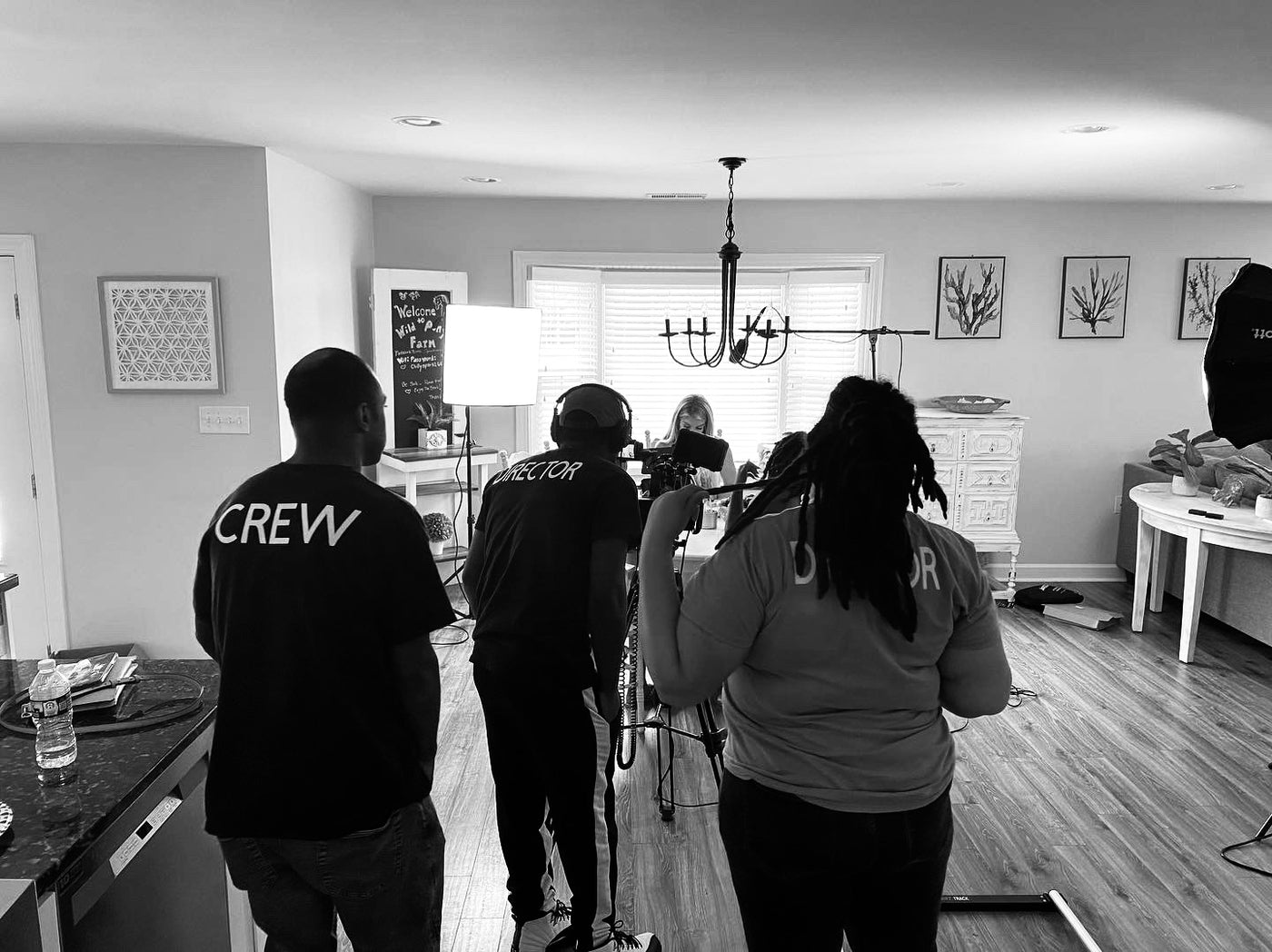 Group of people in a room with 'CREW' on their backs, possibly a film or video production setting.